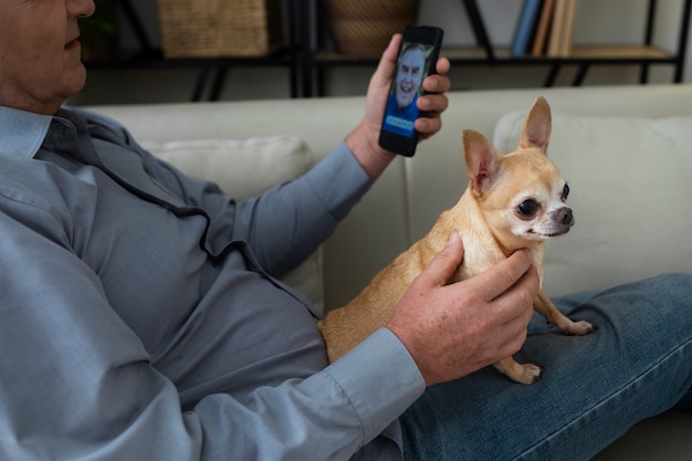 Free Photo man using a smartphone at home next to his dog