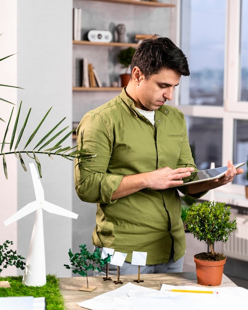 Man using tablet next to an eco-friendly wind power project layout