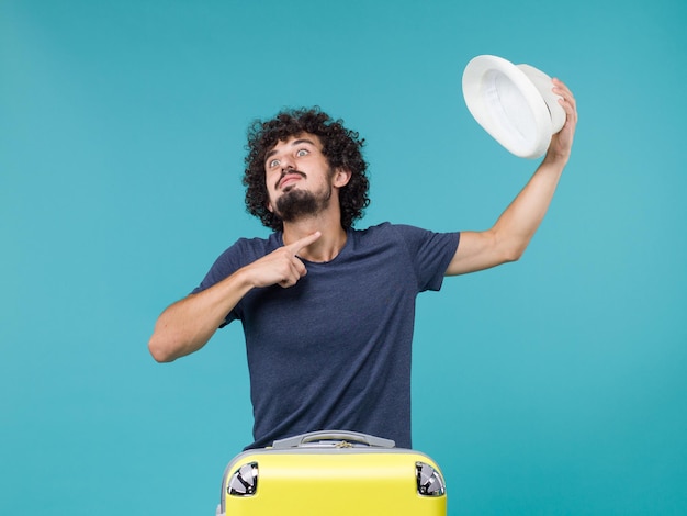 Free photo man in vacation holding his hat on blue floor voyage journey summer vacation sea plane