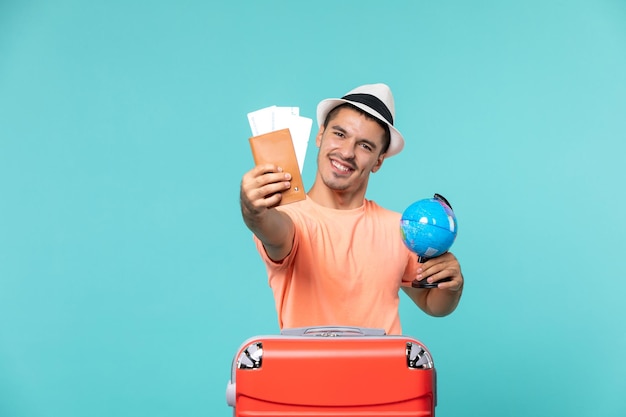 man in vacation holding little globe and tickets on light-blue