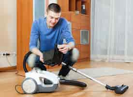 Free photo man  vacuuming with vacuum cleaner on parquet floor in living room