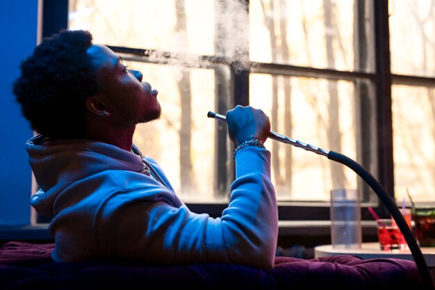 Man vaping from a hookah indoors