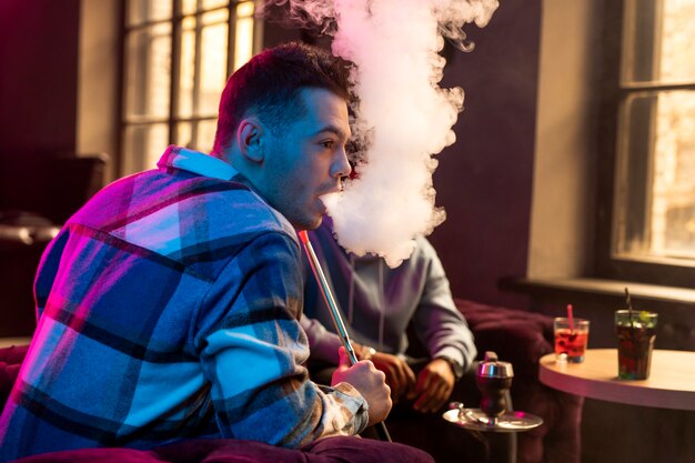 Man vaping from a hookah indoors