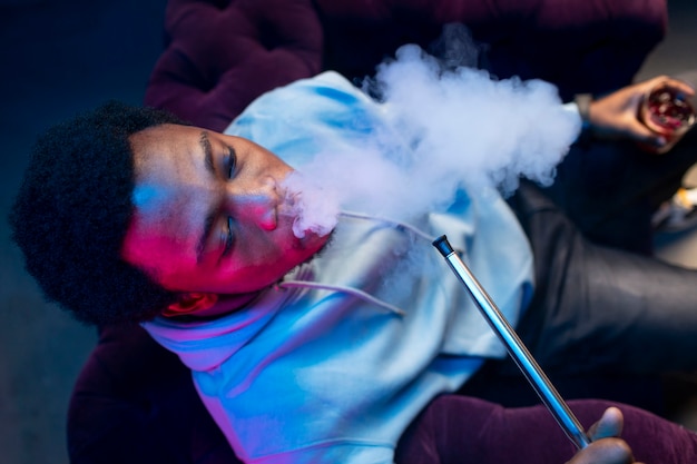 Free photo man vaping from a hookah indoors