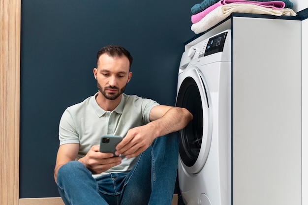 Free photo man waiting for the washing machine to finish its program