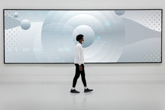 Free Photo man walking in front of a large billboard