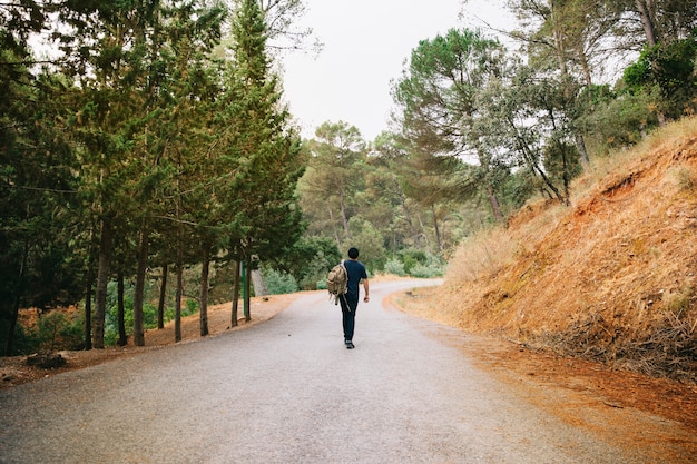 Free Photo man walking on road in forest