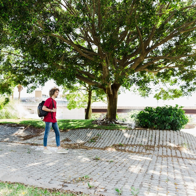 Man walking with backpack near tree