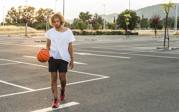 Free photo man walking with basketball in court