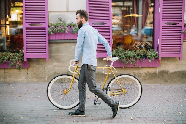 Man walking with bicycle near pink windows