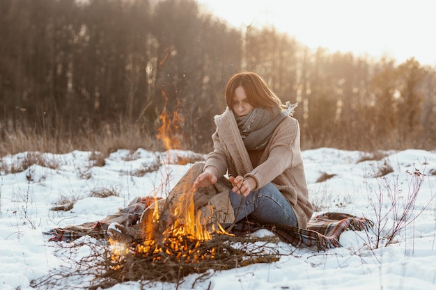 Free Photo man warming up next to a campfire in winter