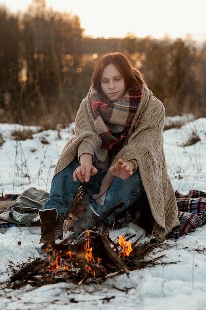 Free photo man warming up next to a campfire in winter