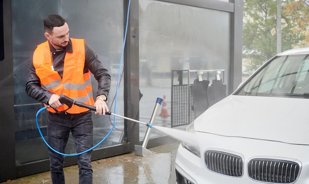 Man washing car on carwash station wearing orange vest