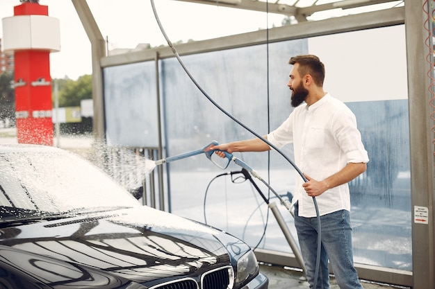 Free photo man washing his car in a washing station