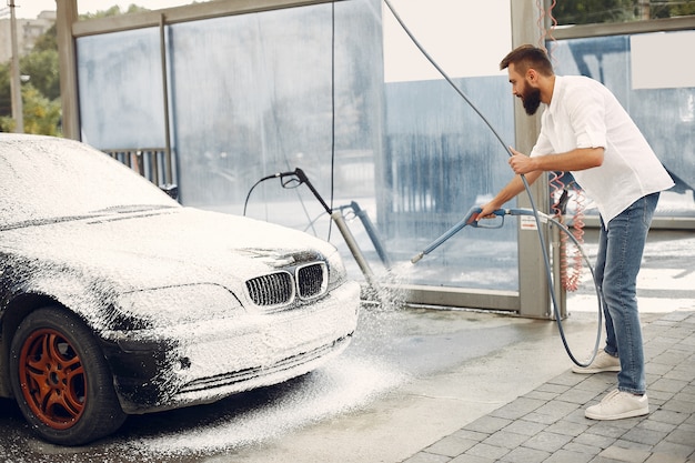 Free photo man washing his car in a washing station