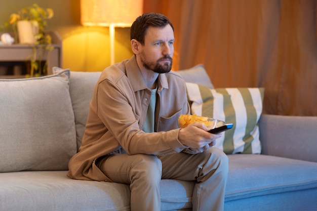 Man watching tv and eating chips