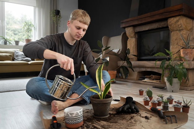 Free photo man watering plant at home full shot