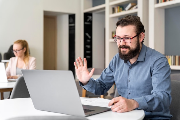 Free Photo man waving at laptop medium shot