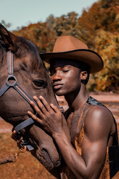 Man wearing brown cowboy hat and hugging horse