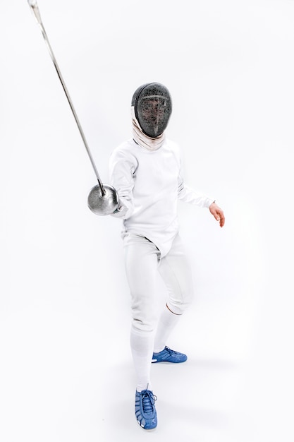 Free photo man wearing fencing suit practicing with sword against gray