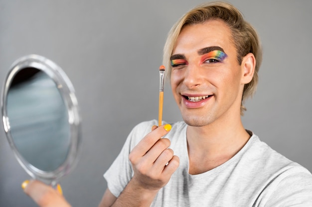 Free photo man wearing make-up cosmetics and holding brush