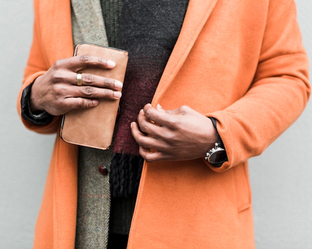 Free Photo man wearing an orange coat holding his wallet