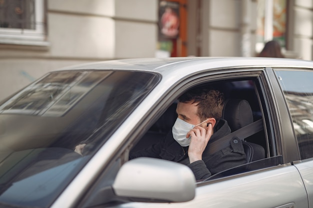 Man wearing a protective mask sitting in a car