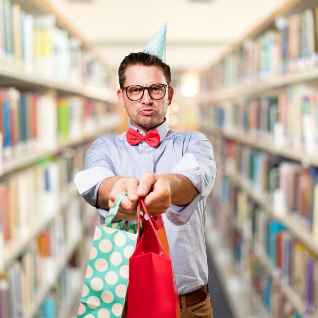 Man wearing a red bow tie and party hat. Holding gift. Looking u