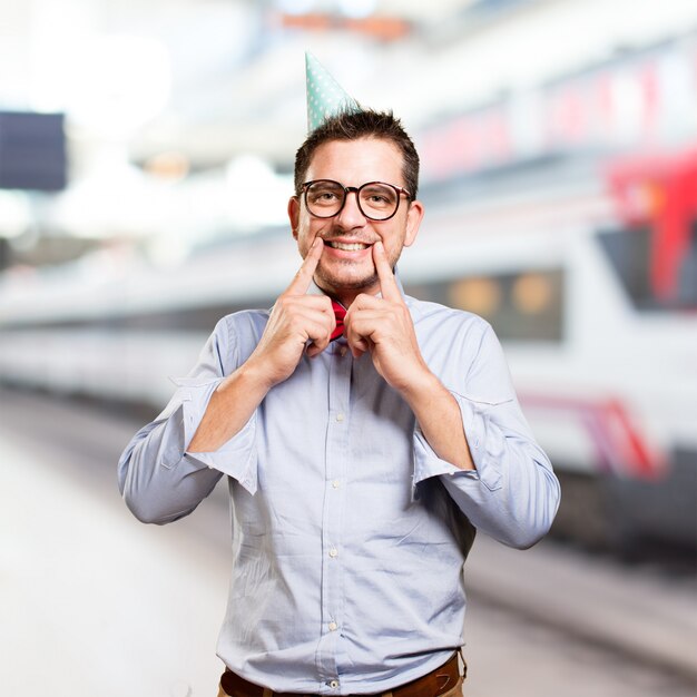 Man wearing a red bow tie and party hat. Smiling.