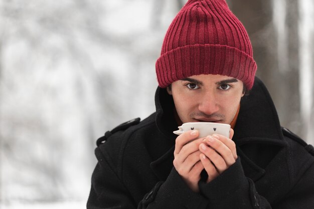 Man wearing red hat holding a cup of tea