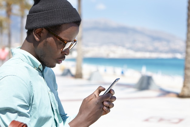 man wearing trendy clothing reading bad news using an electronic device