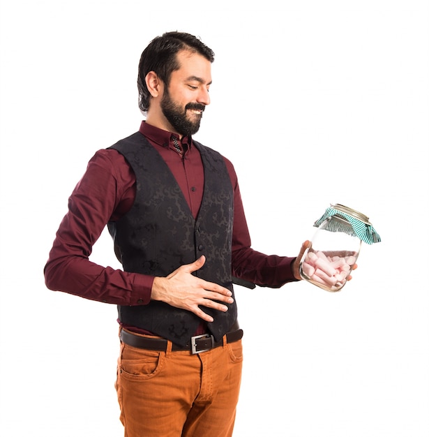 Free photo man wearing waistcoat holding glass jar with sweets inside