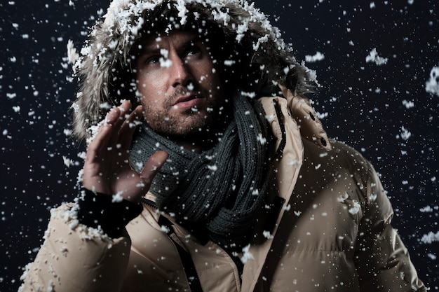 Free photo man wearing a winter jacket while it's snowing