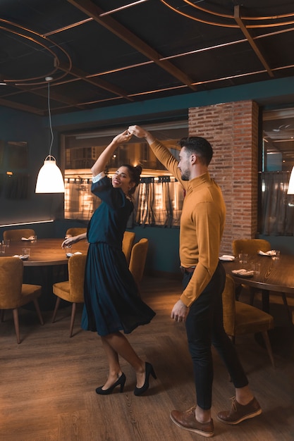 Free Photo man whirling cheerful woman in restaurant