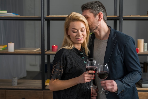 Man whispering to blond woman with glasses of wine 