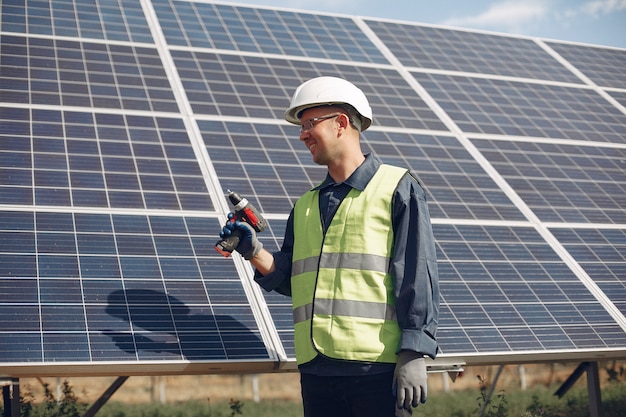 Man in a white helmet near a solar panel