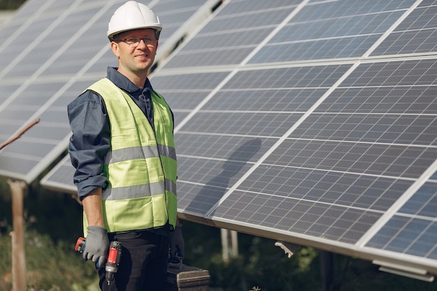 Man in a white helmet near a solar panel