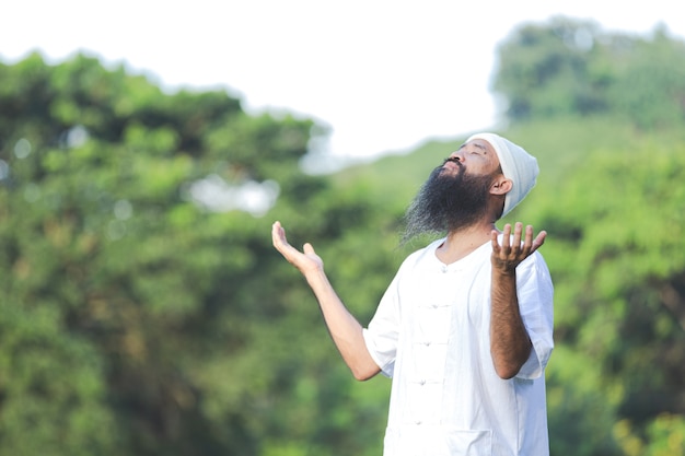 Man in white outfit meditating in nature