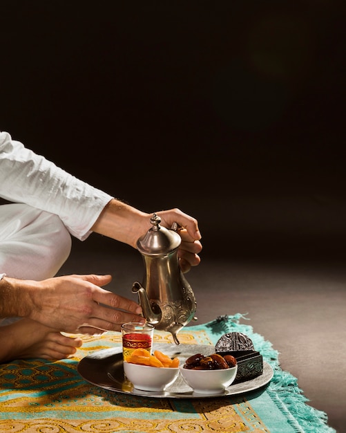 Free photo man in white pouring tea in tiny cup front view