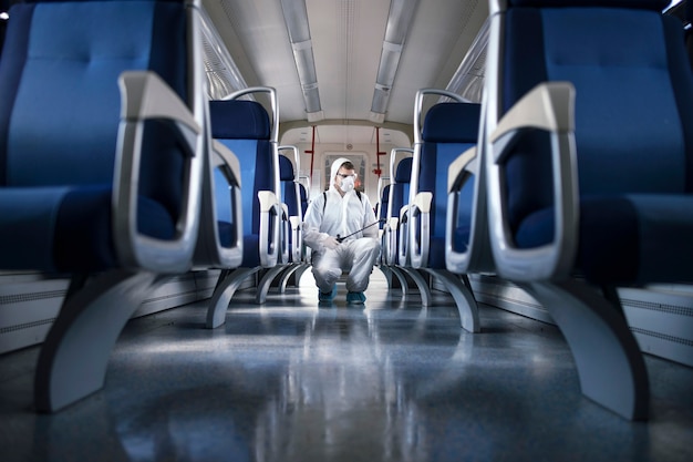 Free photo man in white protection suit disinfecting and sanitizing subway train interior to stop spreading highly contagious corona virus