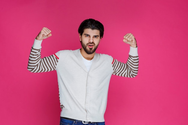 Man in white shirt demonstrating his arm muscles and power. 