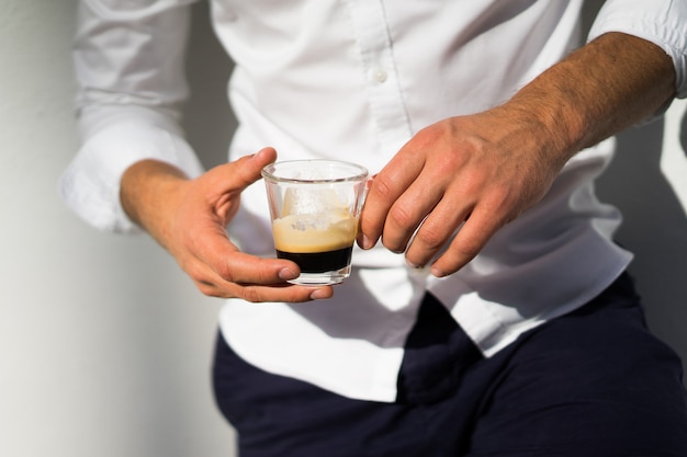 man in white shirt drinks coffee outdoors in summer