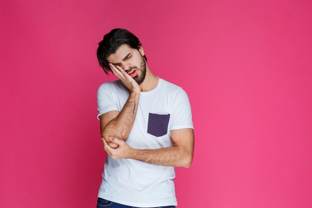 Man in white shirt looks exhausted and sleepy.