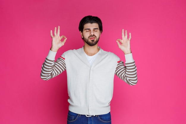 Man in a white shirt making full satisfaction or meditation hand sign. 