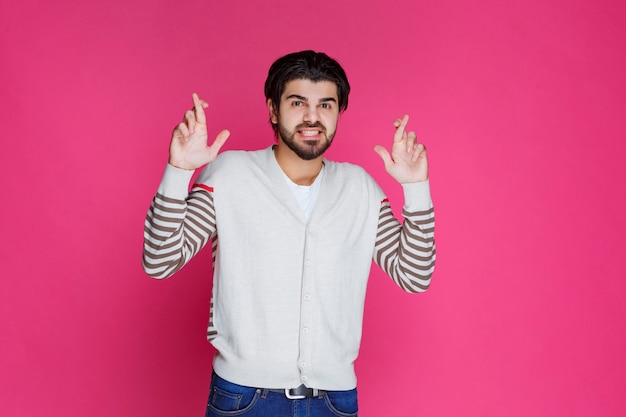 Man in a white shirt making hand cross sign. 