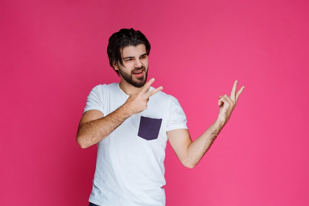 Man in white shirt making peace hand sign and sending message.