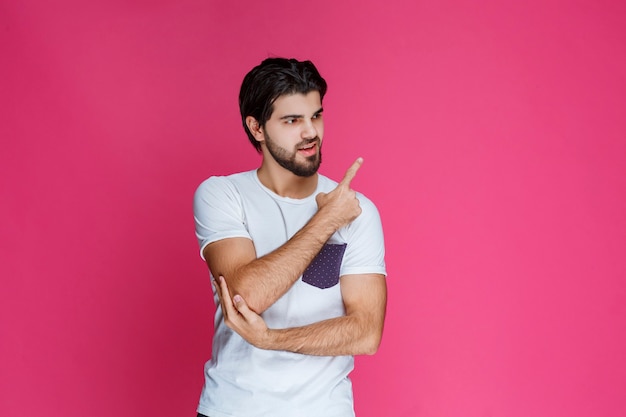 Man in white shirt pointing and presenting something in the right side.