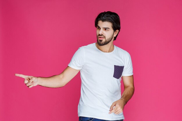 Man in white shirt pointing at something on the left. 