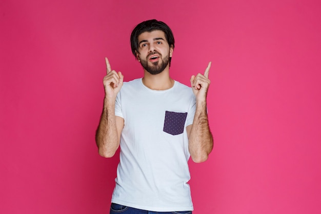 Man in white shirt pointing to something with his pointing finger.