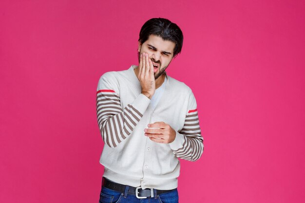 Man in a white shirt putting his hand to his face. 